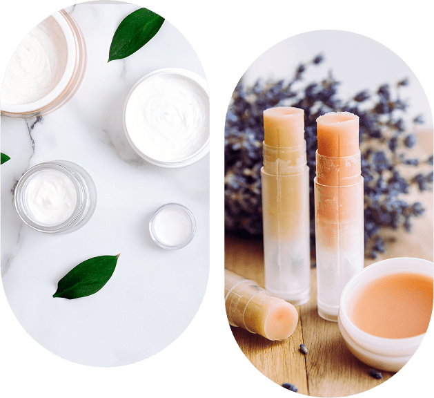 Skin care products, including creams in jars and lip balms in tubes, are displayed on a marble surface with green leaves and lavender in the background.