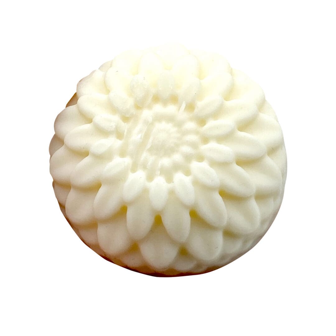 An off-white Apple Maple Bourbon Lotion Bar featuring a carved floral pattern on top, resembling a large, detailed daisy.
