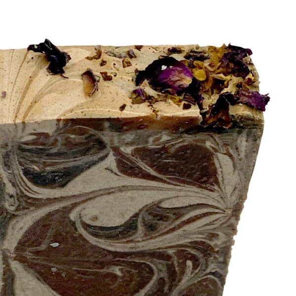 Close-up of the Black Amber & Lavender handcrafted soap bar featuring swirled brown and beige patterns, topped with dried flower petals.
