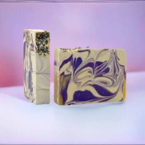Two "Loving Lavender" artisanal soap bars showcase purple and cream swirls adorned with dried herbs, set against a pink and white gradient backdrop.