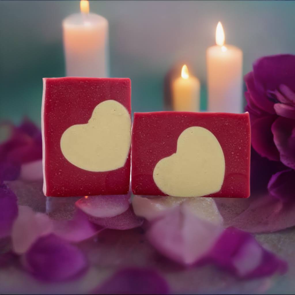 Two Love Spell heart-themed red soaps featuring white heart designs, surrounded by rose petals and lit candles.