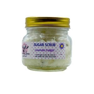 A small jar labeled "Loving Lavender Sugar Scrub" with a yellow lid features ingredients including cane sugar, coconut oil, olive oil, vitamin E, jojoba oil, lemon oil, and lavender buds.
