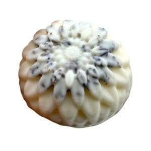 The Loving Lavender Lotion Bar is a white, flower-shaped soap adorned with gray-blue speckles, layered petal details, and a textured surface.