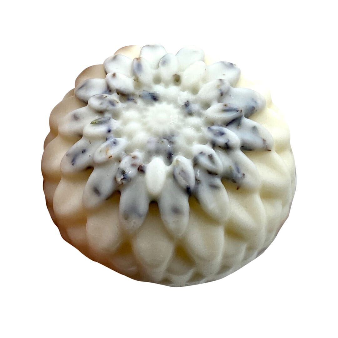 The Loving Lavender Lotion Bar is a white, flower-shaped soap adorned with gray-blue speckles, layered petal details, and a textured surface.