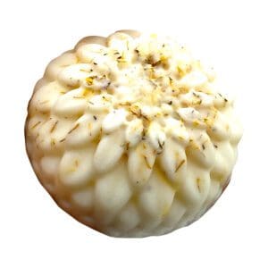 The Seventh Heaven Lotion Bar is a round, white, flower-shaped soap featuring small dried herb pieces on its surface, displayed against a white background.