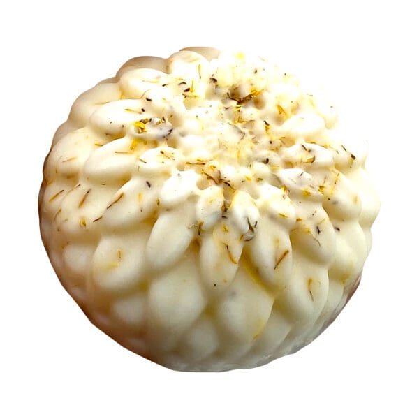 The Seventh Heaven Lotion Bar is a round, white, flower-shaped soap featuring small dried herb pieces on its surface, displayed against a white background.